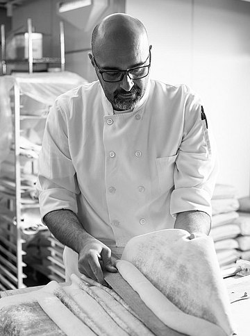 Der Chefbäcker formt Brotteig zu Baguettes 