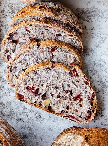 Ein aufgeschnittener Laib Brot mit Beeren und Nüssen